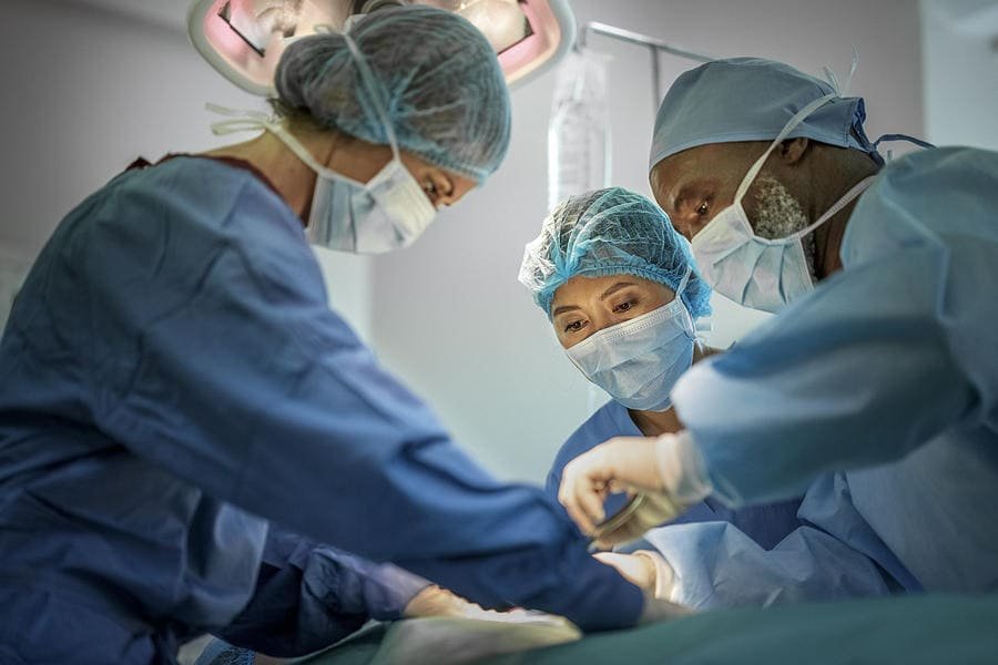 Three surgeons operating on a patient.