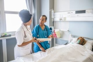 Two Nurses at a patient's bedside.